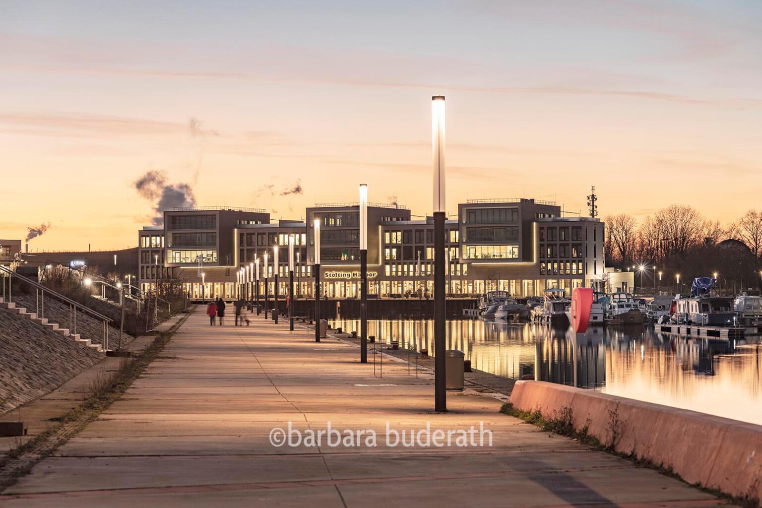 Promenade am Stölting Harbour in Gelsenklirchen mit erleuchteten Strassenlaternen und Spaziergängern