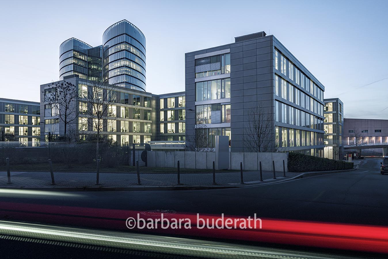 Architekturaussenaufnahme auf erleuchtete Bürogebäude mit der EON Konzernzentrale in Essen im Hintergrund und Lichtstreifen von Autos im Vordergrund am Abend