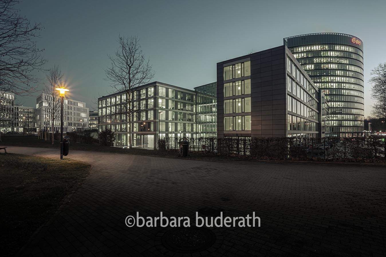 Beleuchteter Fussgängerweg am Abend entlang der Konzernzentrale der EON AG in Essen