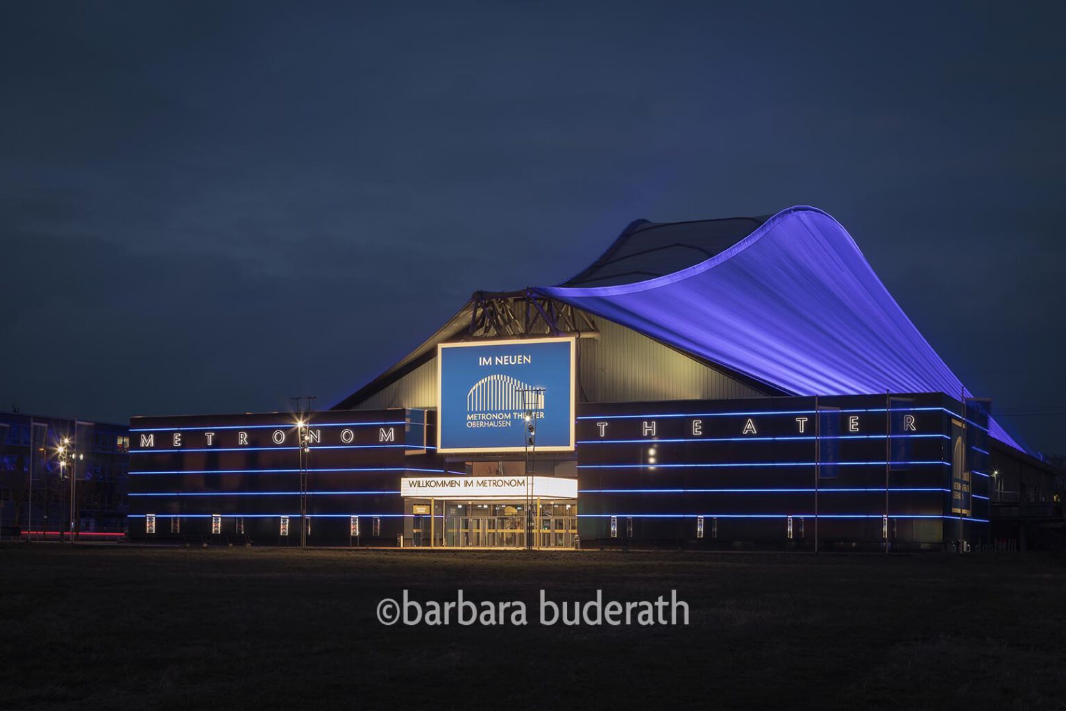 Seitenansicht des erleuchtenen Metronom Theaters mit Seitenansicht in Oberhausen am Abend