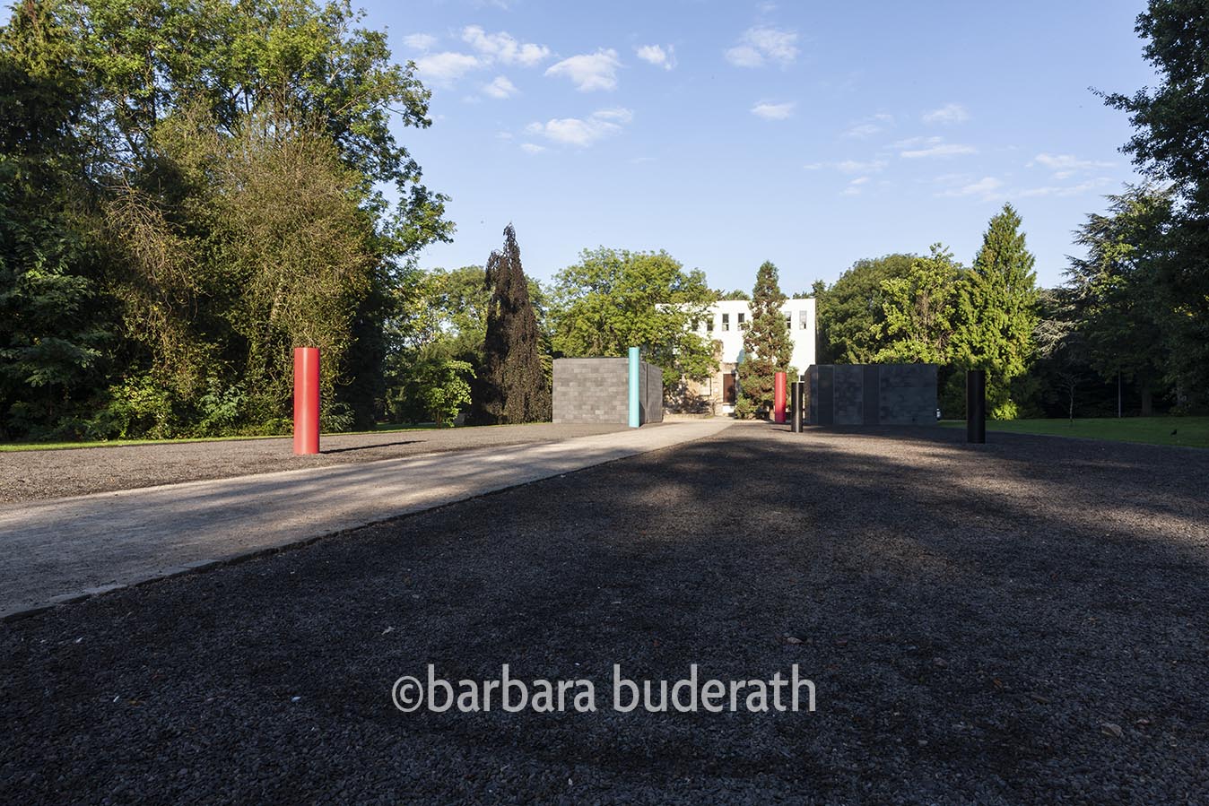 Schooterweg durch den Park von Haus Weitmar auf das Museum unter Tage und auf Haus Weitmar zu. Am Rand stehen rote und blaue runde stehlen.